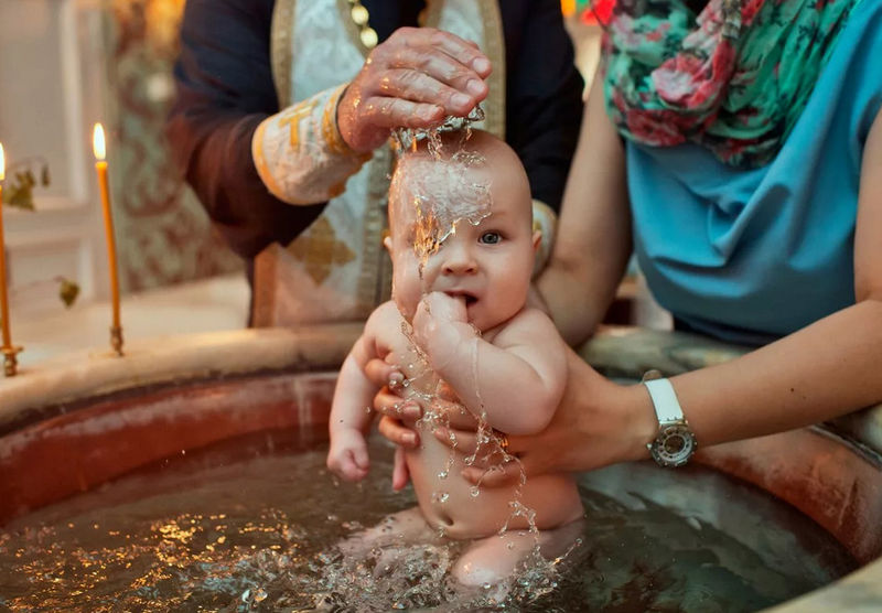 Ребенка крестят в церкви